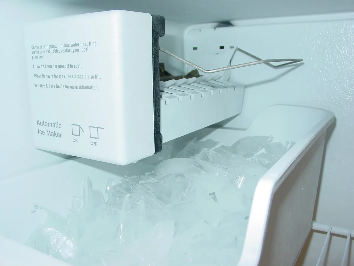 Automatic ice maker module mounted inside a freezer above the ice bin