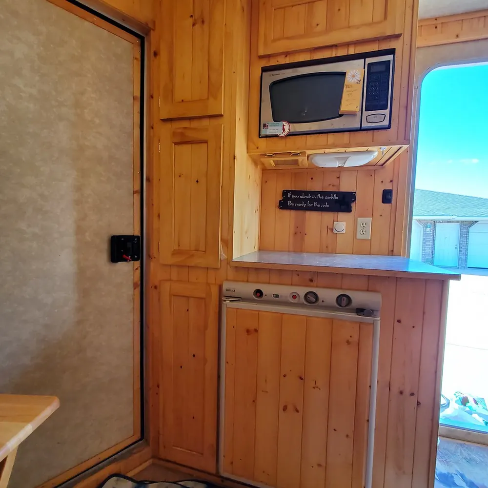 Small undercounter refrigerator set into wood cabinets below a built-in microwave