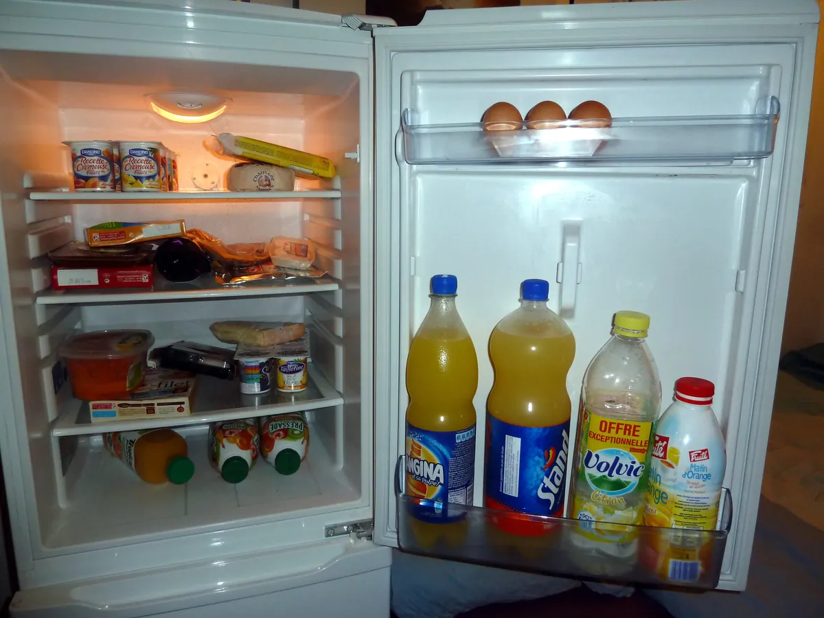 Open refrigerator with food on the shelves and bottles in the door bins