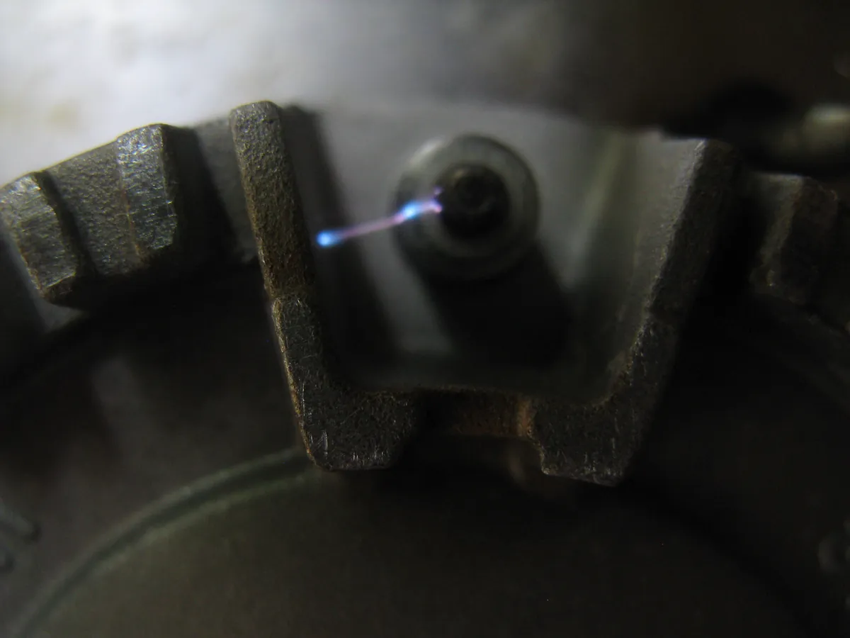 Close view of a gas burner igniter giving off a blue spark
