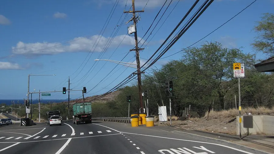 Town street meeting the highway on the Ewa plain, with dry brown hills behind it