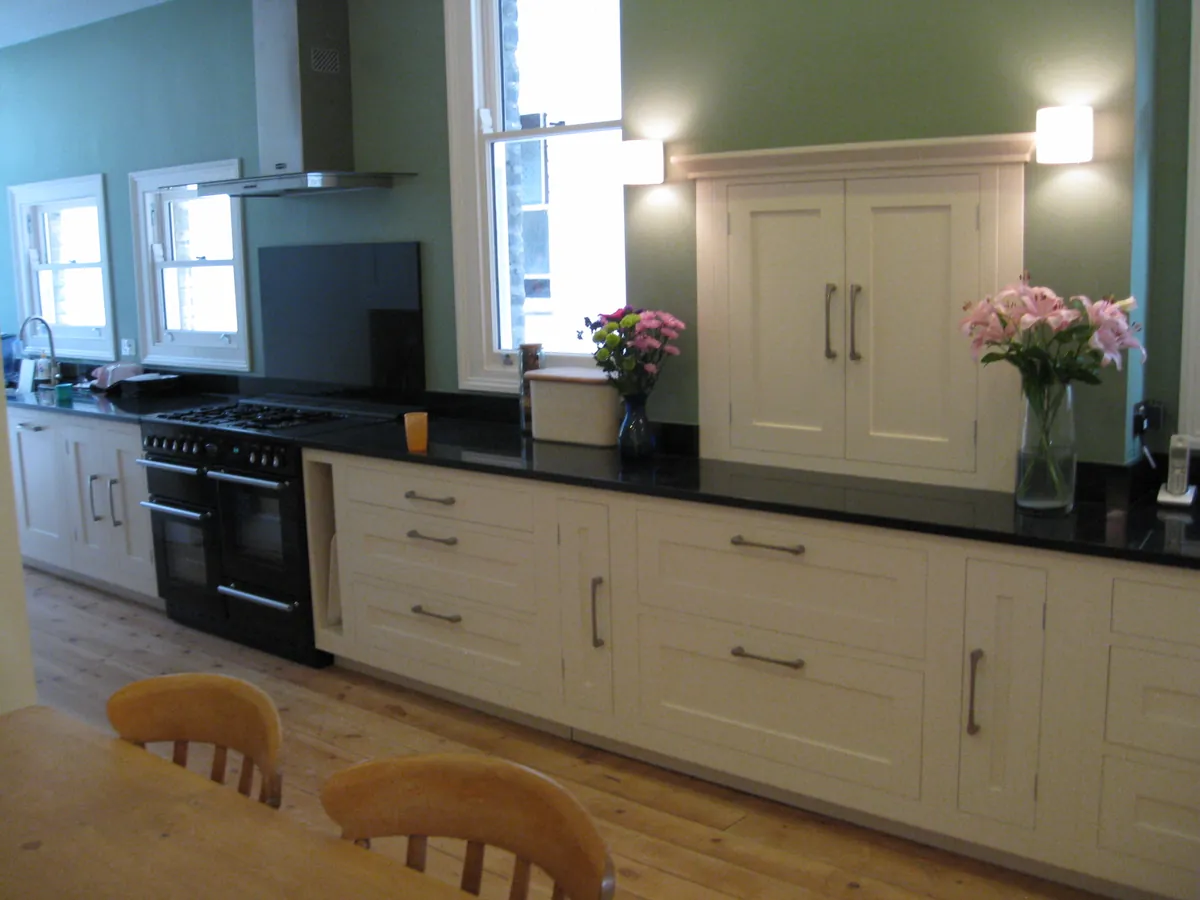 Kitchen with a black range under a hood and cream cabinets
