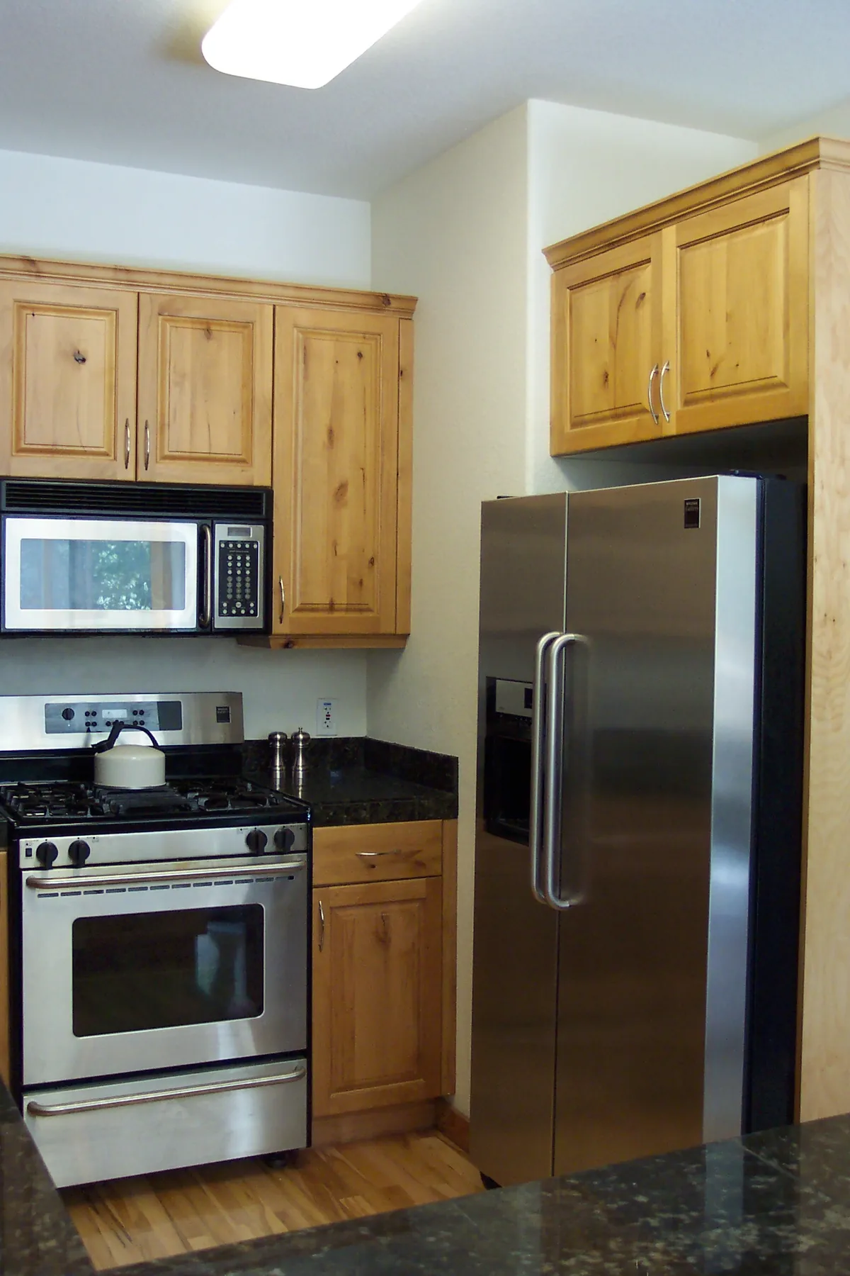Stainless side-by-side refrigerator beside a gas range in a small kitchen