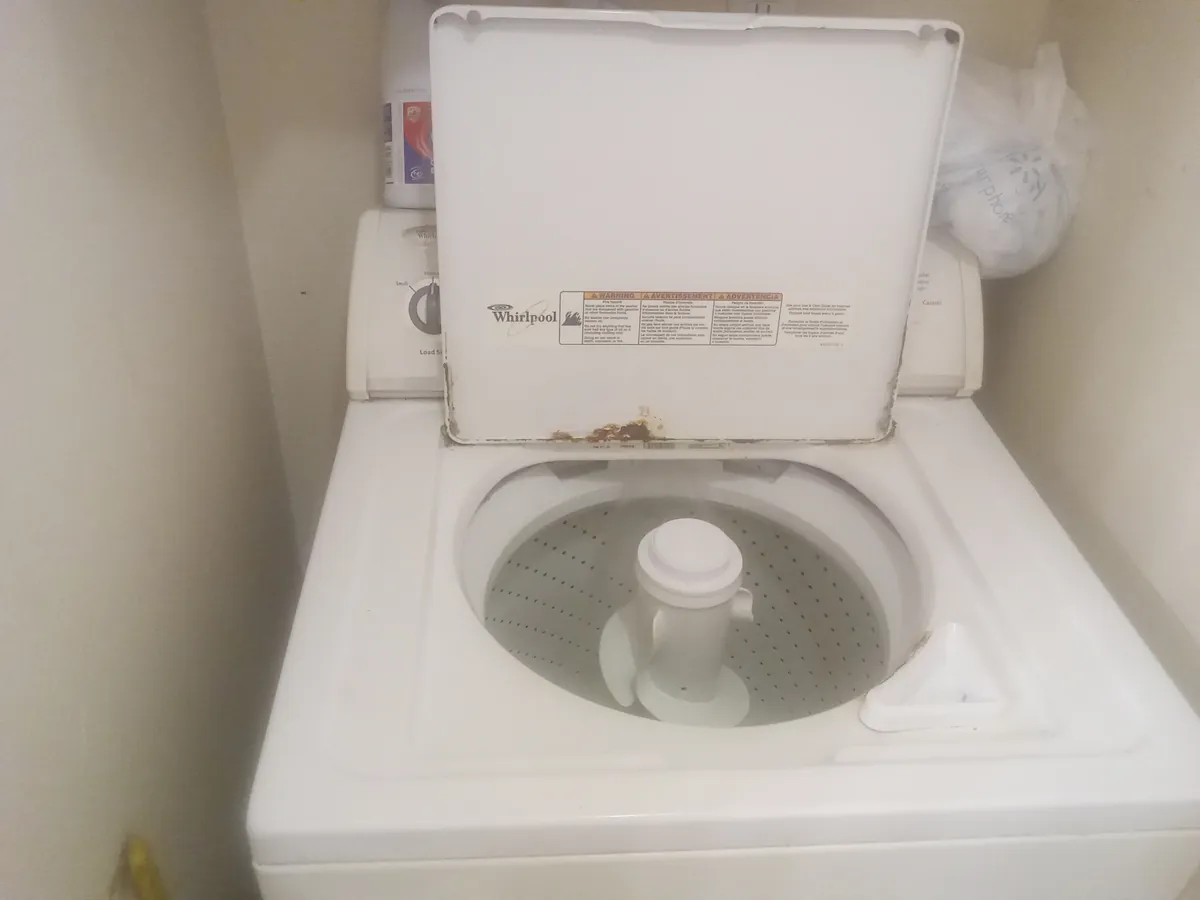 Top-load washer with its lid raised and a tall center agitator inside the basket